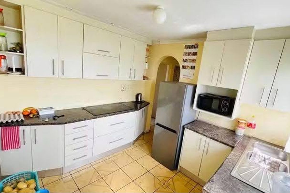 Functional kitchen featuring ample built-in cabinetry, laminate countertops, a stainless steel sink, and ceramic tile flooring.