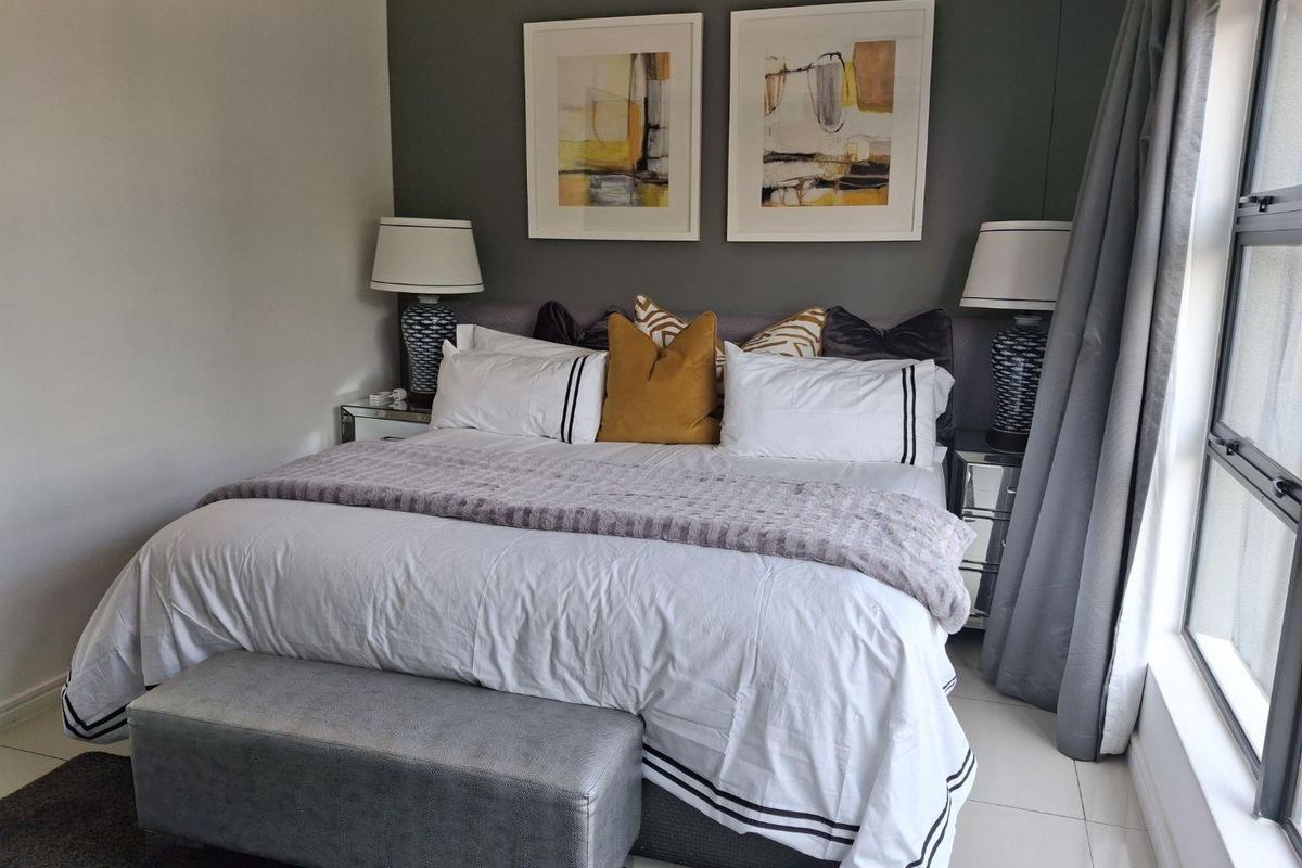 A well-maintained bedroom featuring tiled flooring and a large window, providing a bright and comfortable living space.