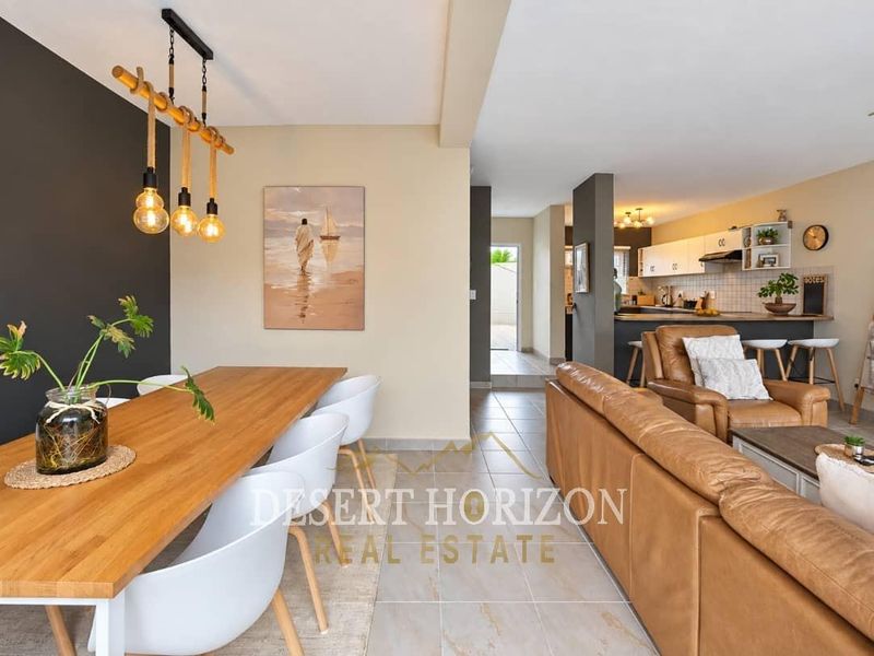 Spacious open-plan living and dining area featuring tiled floors, a modern kitchen with breakfast bar, and neutral wall finishes.