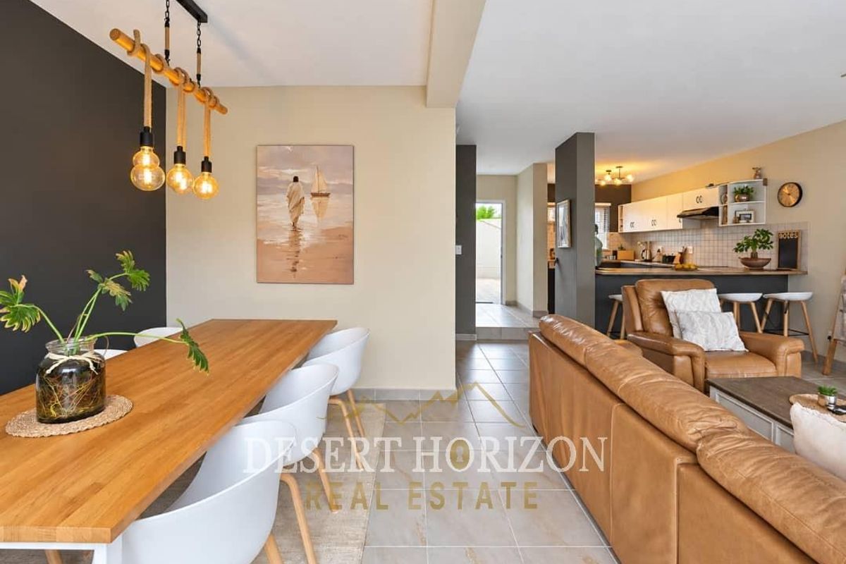 Spacious open-plan living and dining area featuring tiled floors, a modern kitchen with breakfast bar, and neutral wall finishes.