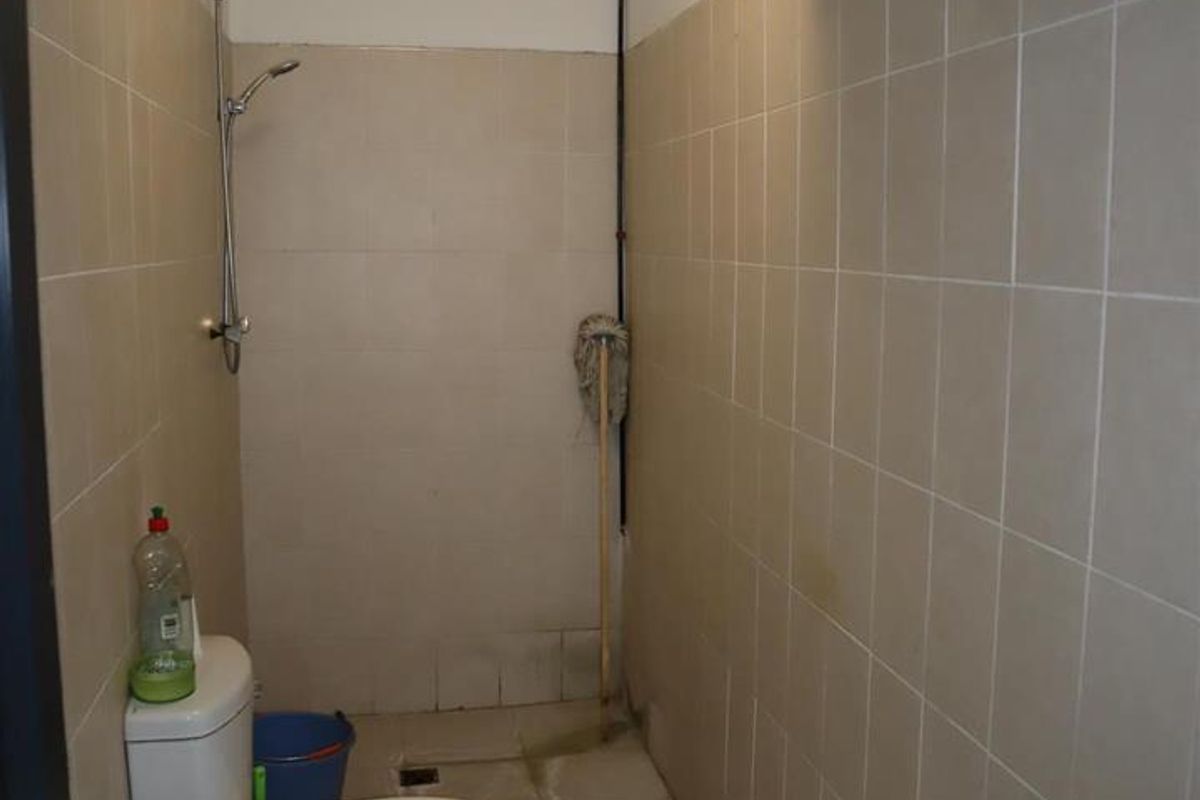 A functional bathroom featuring a shower area, toilet, wall-mounted geyser, and tiled finishes throughout.