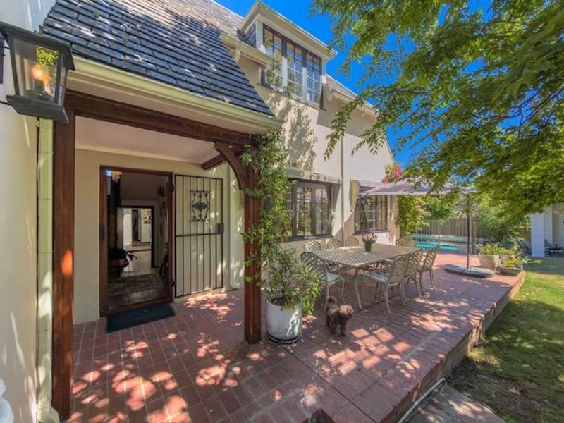 A charming covered brick patio area featuring a timber pergola, providing a seamless transition between the interior living space and the rear garden.