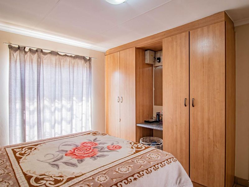 A bedroom featuring light wood-finish built-in wardrobes with an integrated vanity area and neutral wall tones.