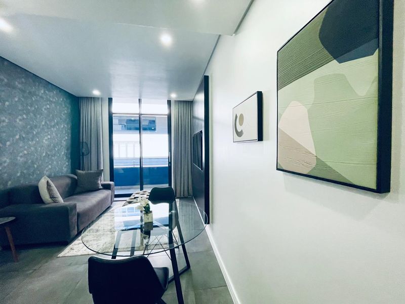 Modern open-plan living area featuring tiled floors, recessed lighting, and a sliding glass door leading to a private balcony.