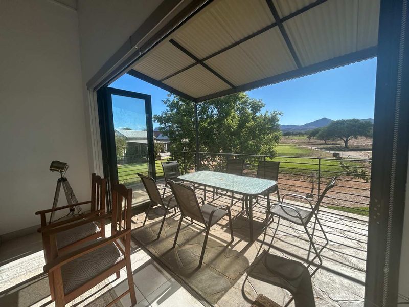 A covered patio featuring folding glass doors, a metal roof, and scenic views of the surrounding landscape.