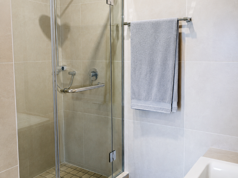 Modern bathroom featuring a glass-enclosed shower with rain shower head, built-in bench, and a separate bathtub with neutral wall tiling.