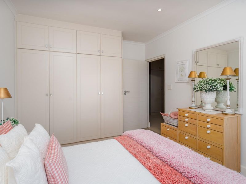 A well-maintained bedroom featuring ample built-in cupboard storage, recessed downlighting, and coved cornicing, creating a clean and functional living space.