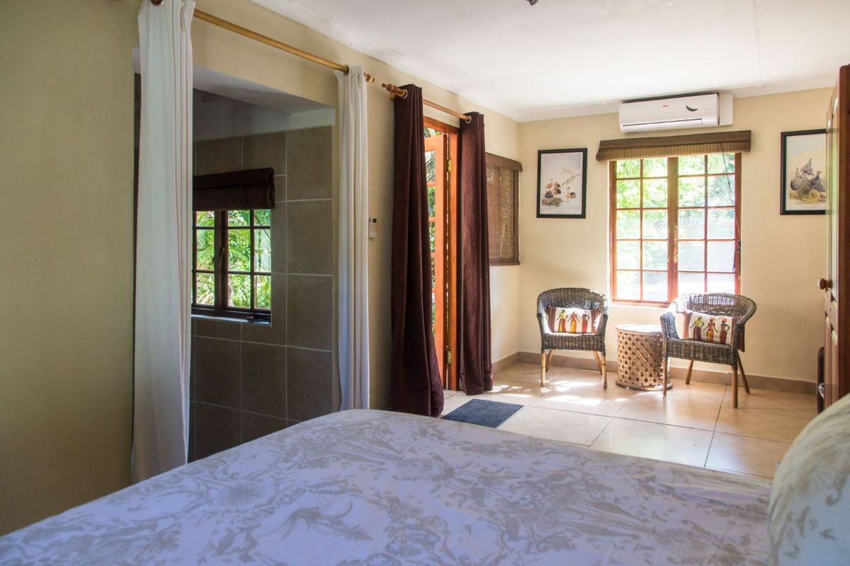 A bedroom featuring tiled flooring, a wall-mounted air conditioning unit, and direct access to an outdoor area through a wooden door.