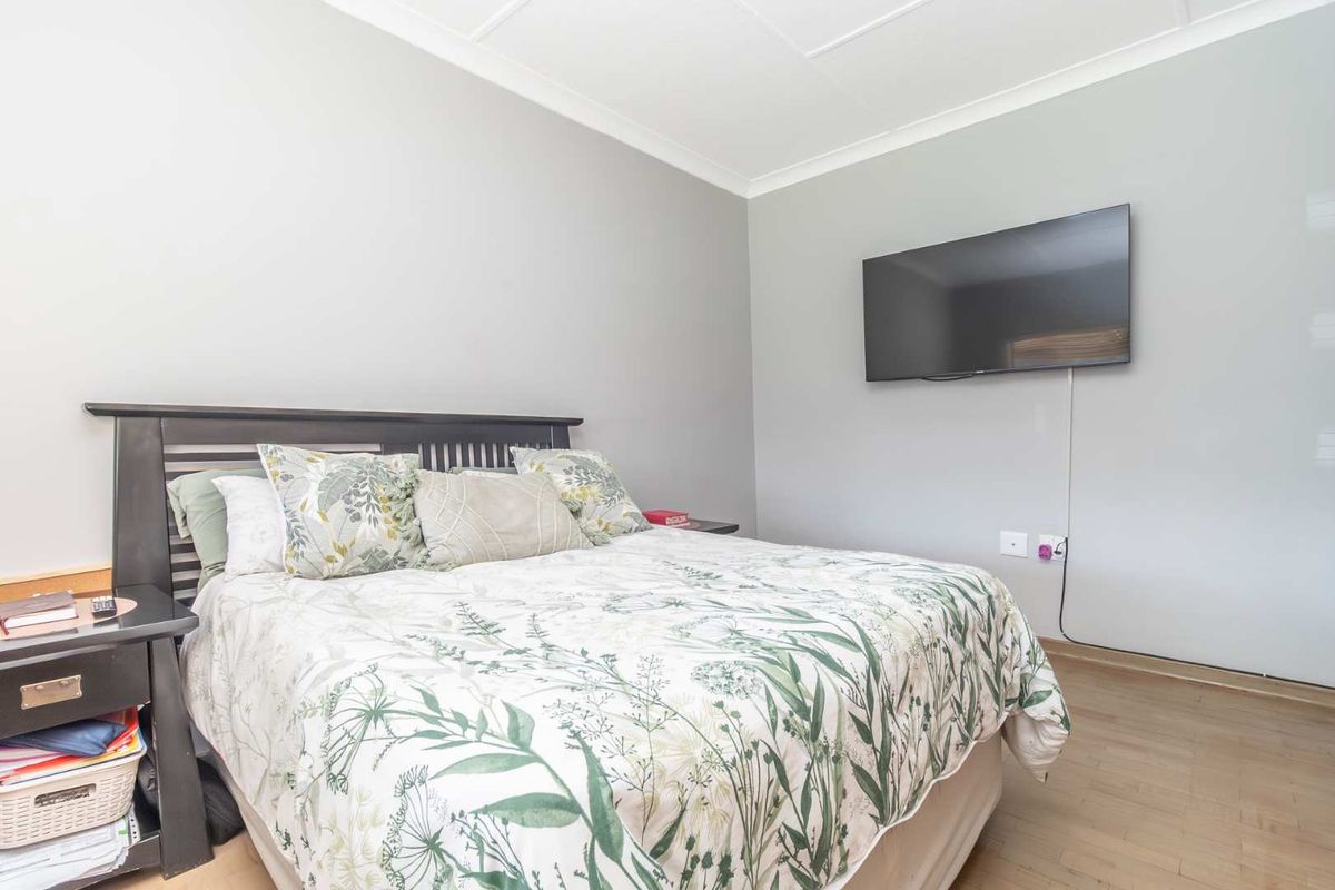 A well-maintained bedroom featuring neutral wall tones, laminate flooring, and a wall-mounted television point.
