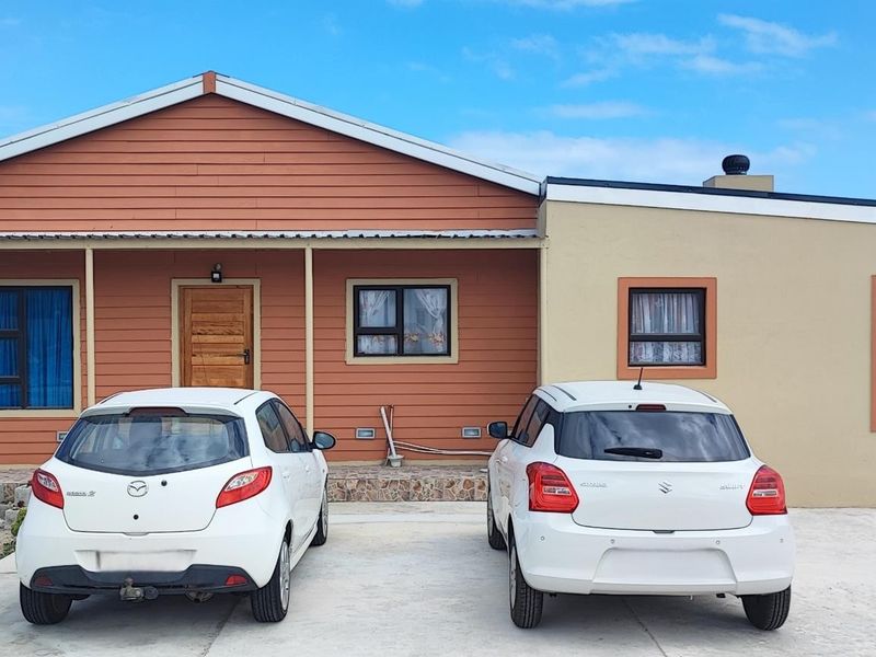 Front elevation of a single-story house featuring a combination of timber cladding and rendered walls with a concrete driveway and covered porch area.