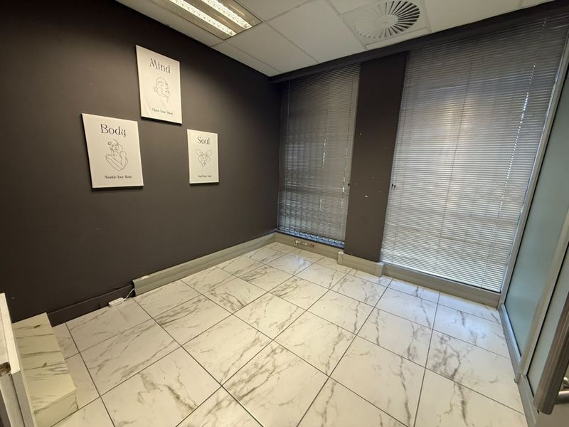 A vacant office space featuring marble-look tiled flooring, recessed ceiling lighting, integrated air conditioning, and venetian blinds on the windows.