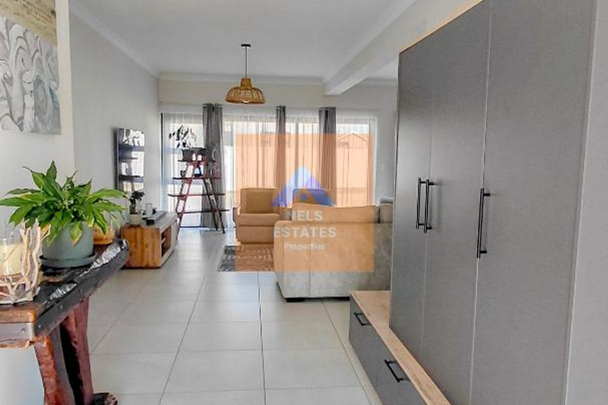 Spacious living area featuring modern grey built-in cabinetry, large format floor tiles, and natural light flowing through sliding glass doors.