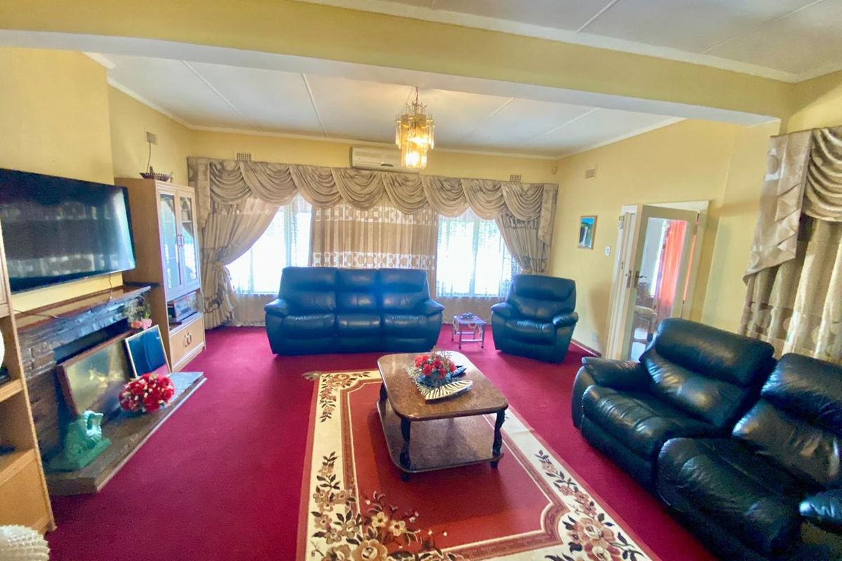 Spacious living room featuring a brick fireplace, split-system air conditioning, and large windows with traditional drapery.
