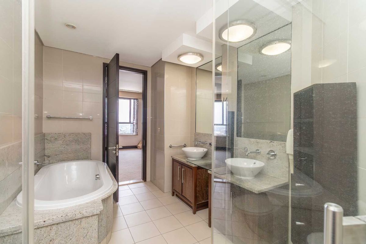 A well-appointed bathroom featuring a built-in bathtub, dual vessel sinks with granite countertops, and a glass-enclosed shower area.