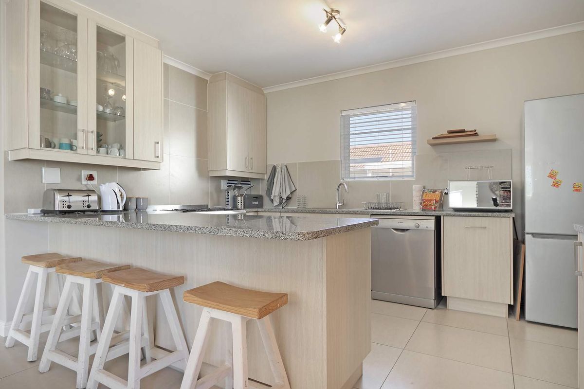A functional kitchen featuring light wood cabinetry, granite countertops, a breakfast bar, and tiled flooring, offering a clean and practical layout.