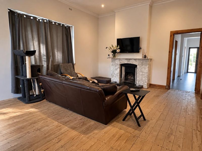 A well-maintained living room featuring polished timber flooring, a classic marble fireplace, and elegant cornice detailing.