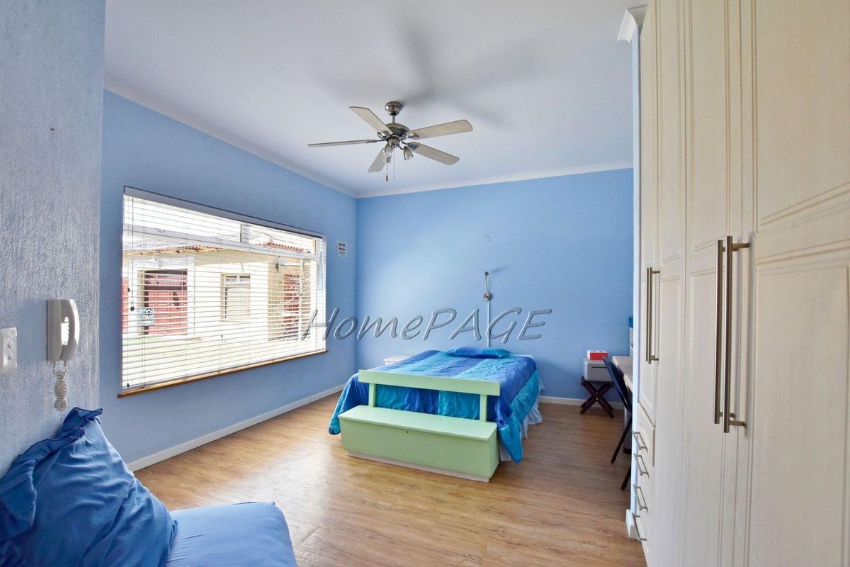 A bedroom featuring light wood-look flooring, built-in cabinetry, and a ceiling fan.