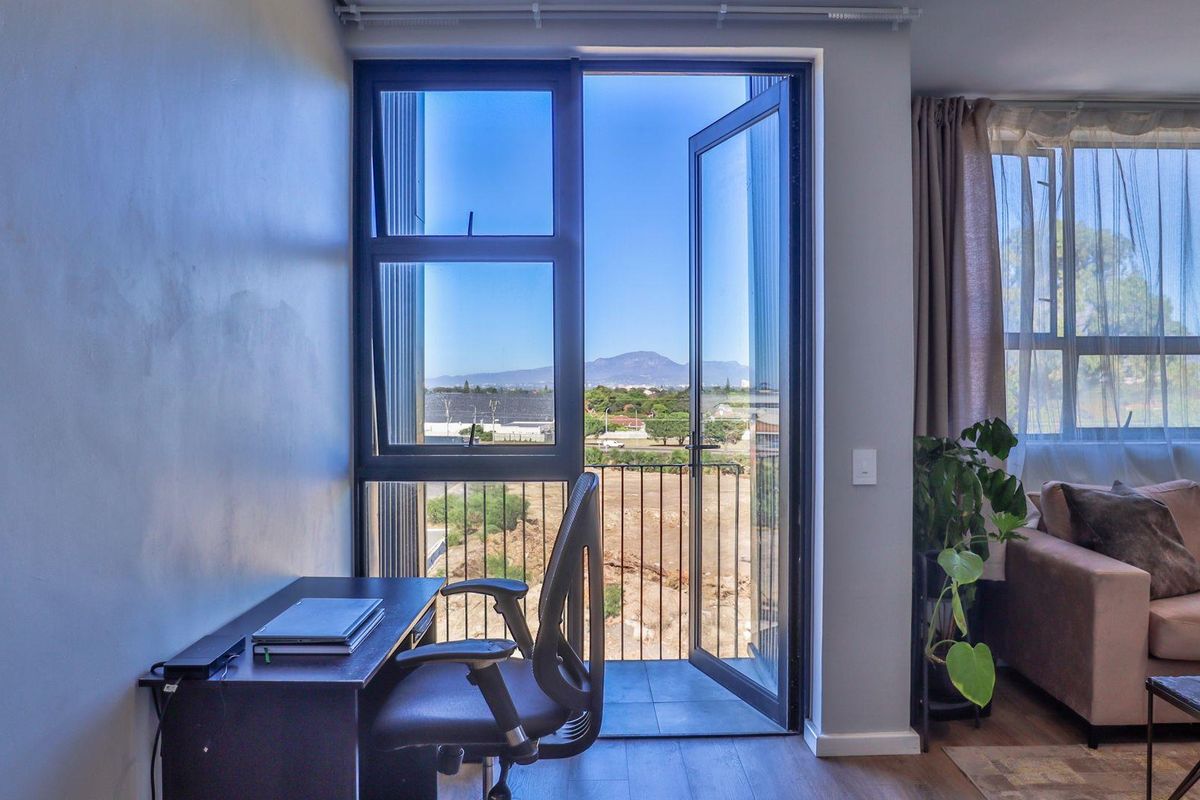 A bright living area featuring a balcony with mountain views, large glass sliding doors, and modern flooring, creating a seamless indoor-outdoor transition.