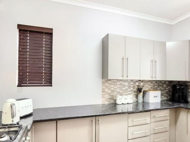 Modern kitchen featuring granite countertops, neutral cabinetry, and a mosaic tile backsplash, providing a clean and functional workspace.