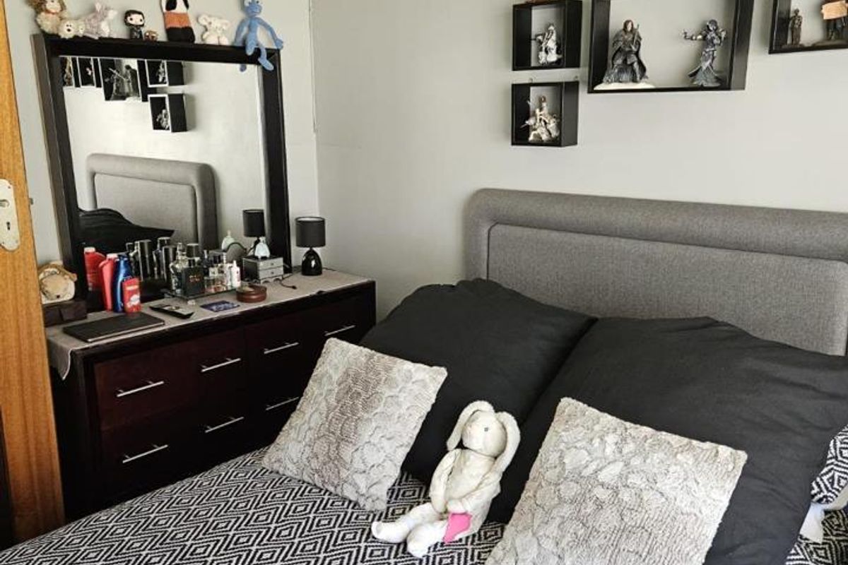 A bedroom featuring a grey upholstered headboard and neutral wall finishes, providing a functional and comfortable sleeping space.