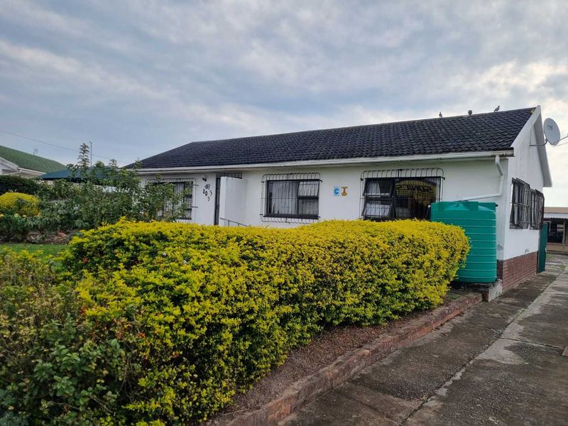 Front elevation of a single-story house featuring a tiled roof, security bars on windows, and a water storage tank in the front garden area.