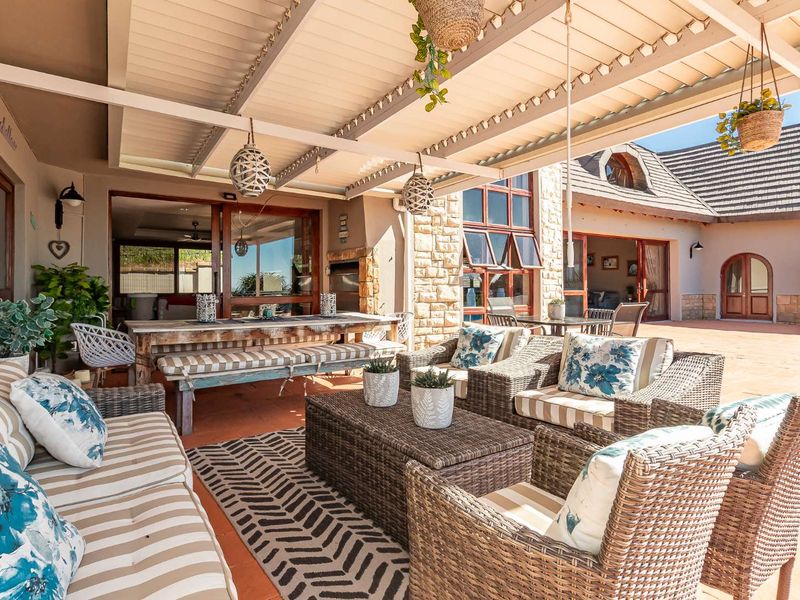 Spacious covered patio featuring stone cladding, tiled flooring, and large sliding glass doors, providing a seamless transition to the interior living spaces.
