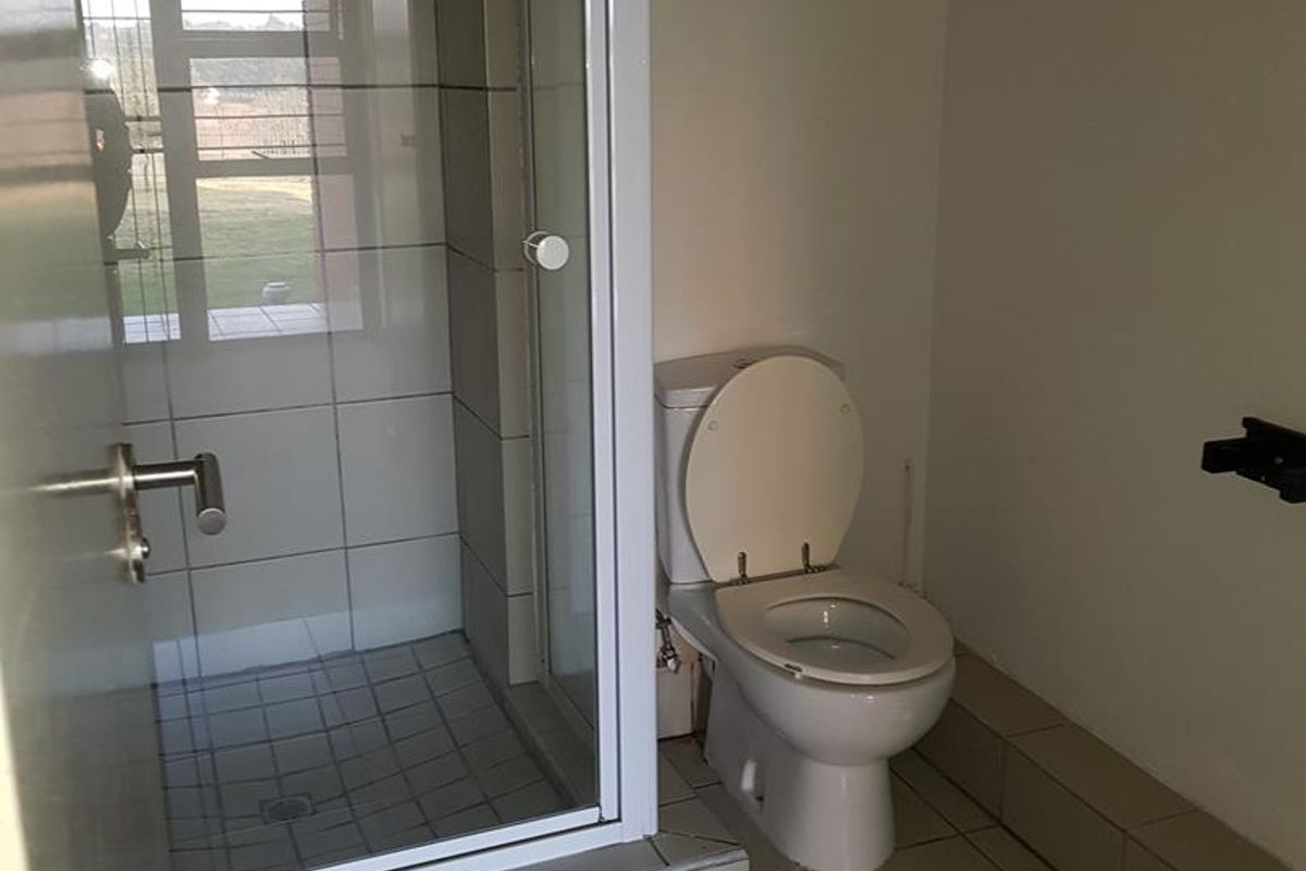 A functional bathroom featuring a tiled shower enclosure with a glass door and a standard white toilet.