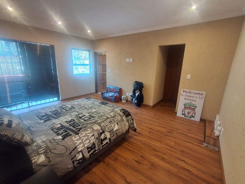 Spacious bedroom featuring laminate flooring, recessed downlighting, and a sliding glass door providing access to the exterior.