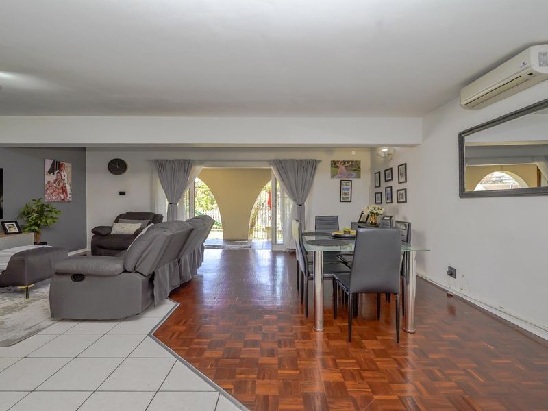 Spacious open-plan living and dining area featuring a mix of parquet and tiled flooring, with direct access to an outdoor patio through sliding doors.