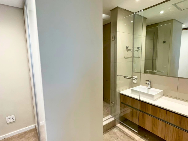 Modern bathroom featuring a sleek double vanity with vessel sinks, large wall mirror, and a glass-enclosed shower area with neutral tiling.
