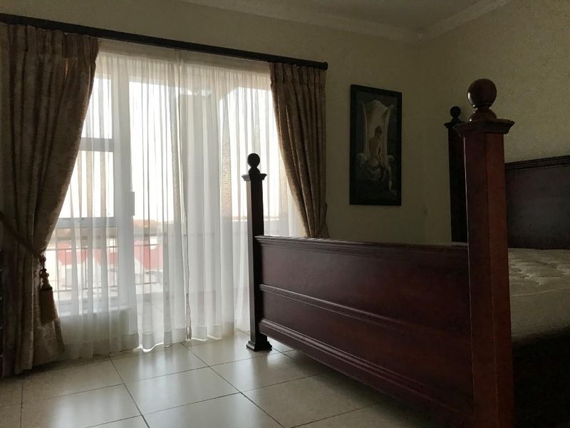 A bedroom featuring tiled flooring and a large sliding glass door providing access to an outdoor area.