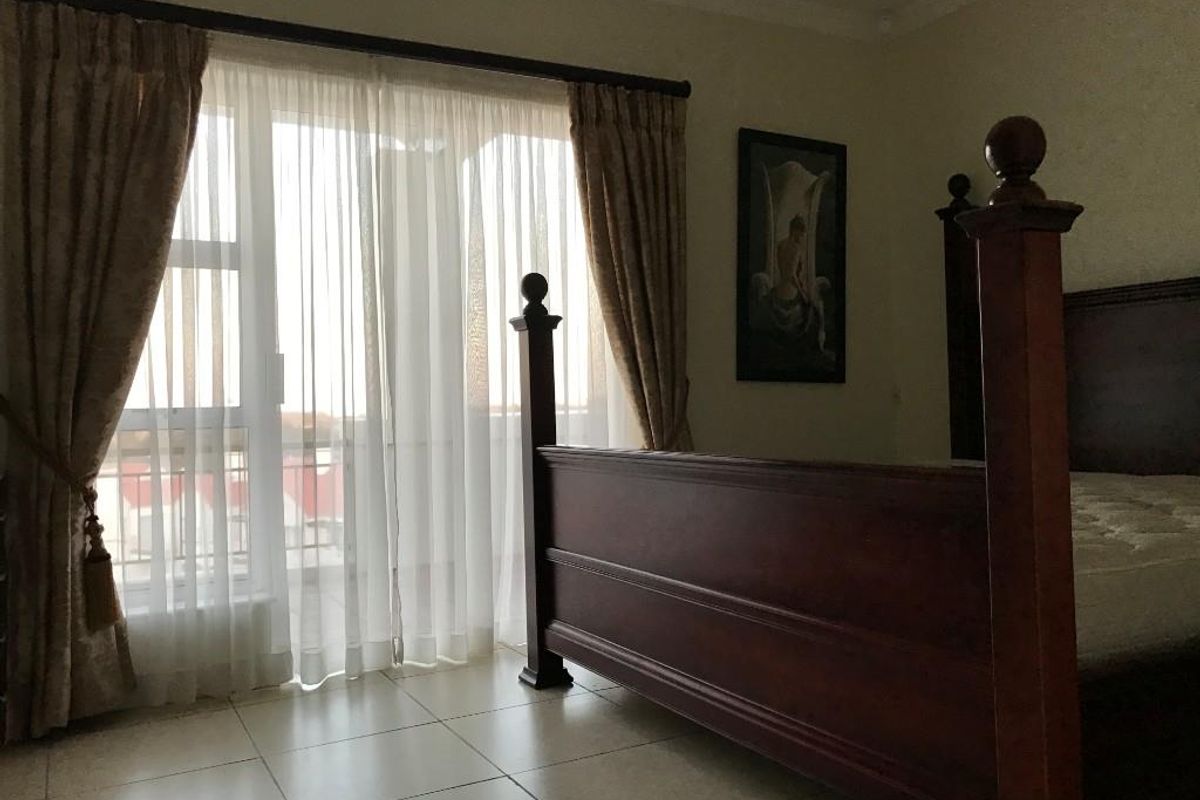 A bedroom featuring tiled flooring and a large sliding glass door providing access to an outdoor area.