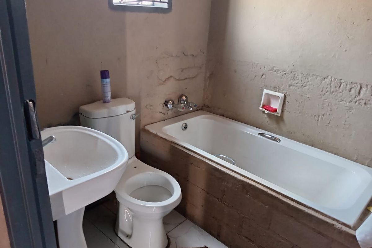 A functional bathroom featuring a standard bathtub, pedestal basin, and toilet, requiring cosmetic updates to the wall finishes.