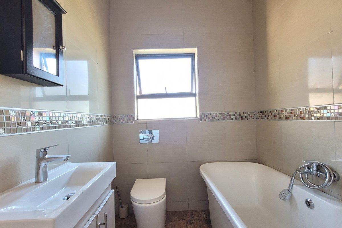 A modern bathroom featuring a wall-mounted vanity, a sleek bathtub with shower mixer, and a wall-hung toilet with tiled walls.