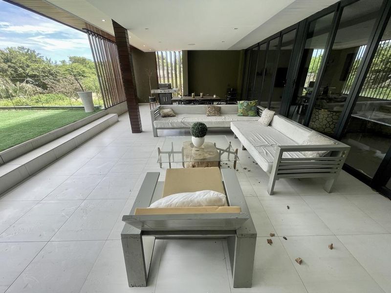 Spacious covered patio featuring large format floor tiles, recessed lighting, and seamless access to the interior through expansive glass sliding doors.
