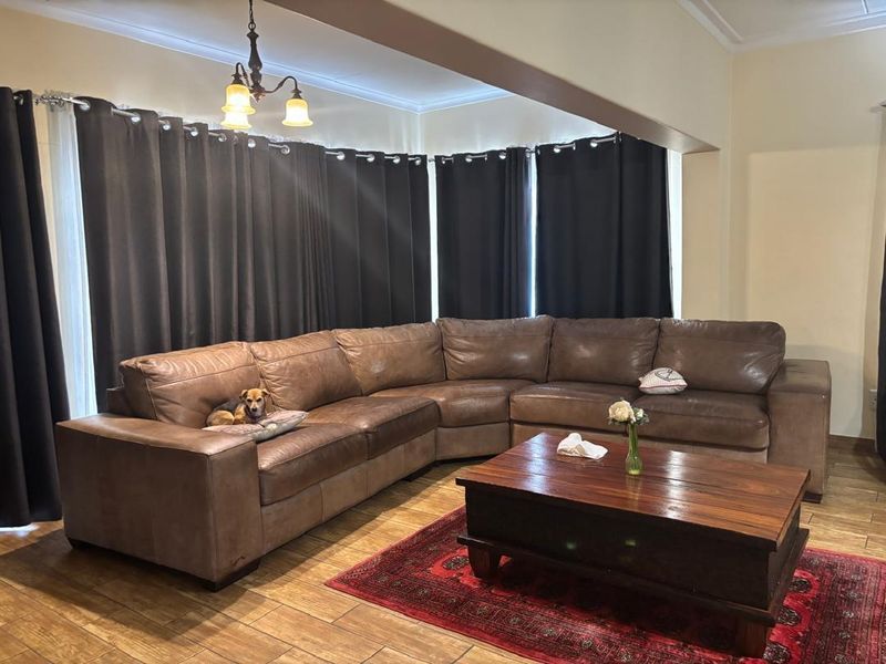 A comfortable living room featuring tiled flooring and a prominent ceiling beam, providing a functional and inviting space for relaxation.