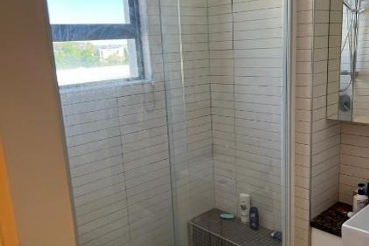 Modern bathroom featuring a glass-enclosed walk-in shower with tiled walls, a built-in shower bench, and a vanity unit.
