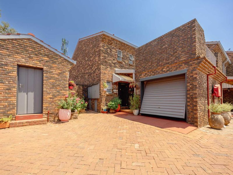 Front exterior view of a face brick townhouse featuring a paved driveway and a single garage with a roll-up door.