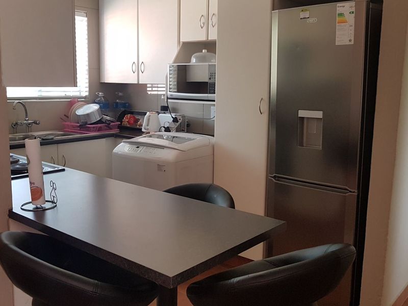 A functional kitchen featuring built-in cabinetry, laminate countertops, and a breakfast bar area, providing efficient workspace and storage in a compact apartment layout.
