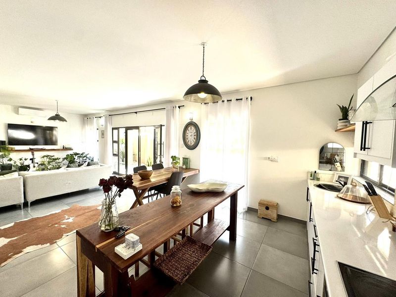 Spacious open-plan living area featuring a modern kitchen with stone countertops, tiled flooring, and seamless flow to the outdoor patio through sliding glass doors.
