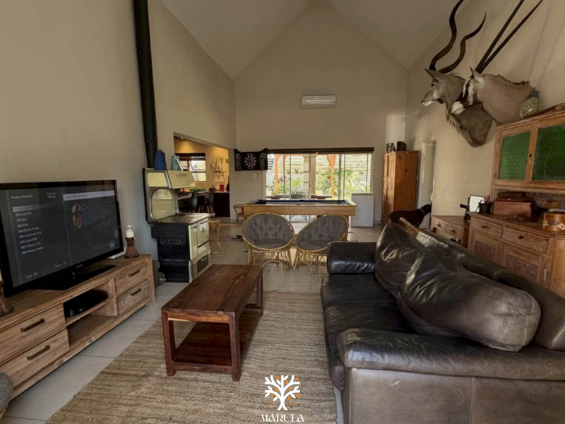 Spacious open-plan living area featuring a high vaulted ceiling, tiled flooring, a wood-burning stove, and integrated air conditioning.