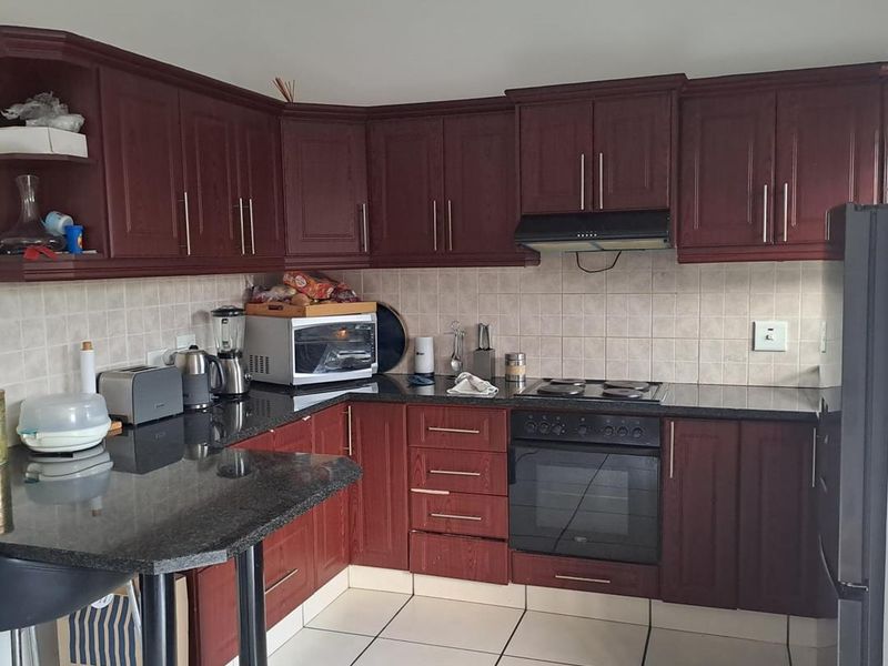 A functional kitchen featuring dark wood cabinetry, granite countertops, a built-in oven with hob, and a tiled backsplash.