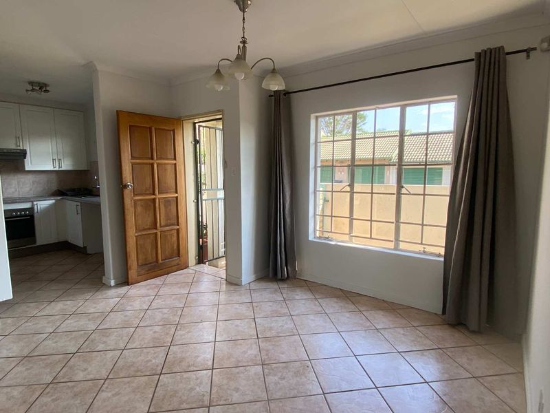 Open plan living and dining area featuring ceramic floor tiles, flowing into a functional kitchen with built-in cabinetry and appliances.
