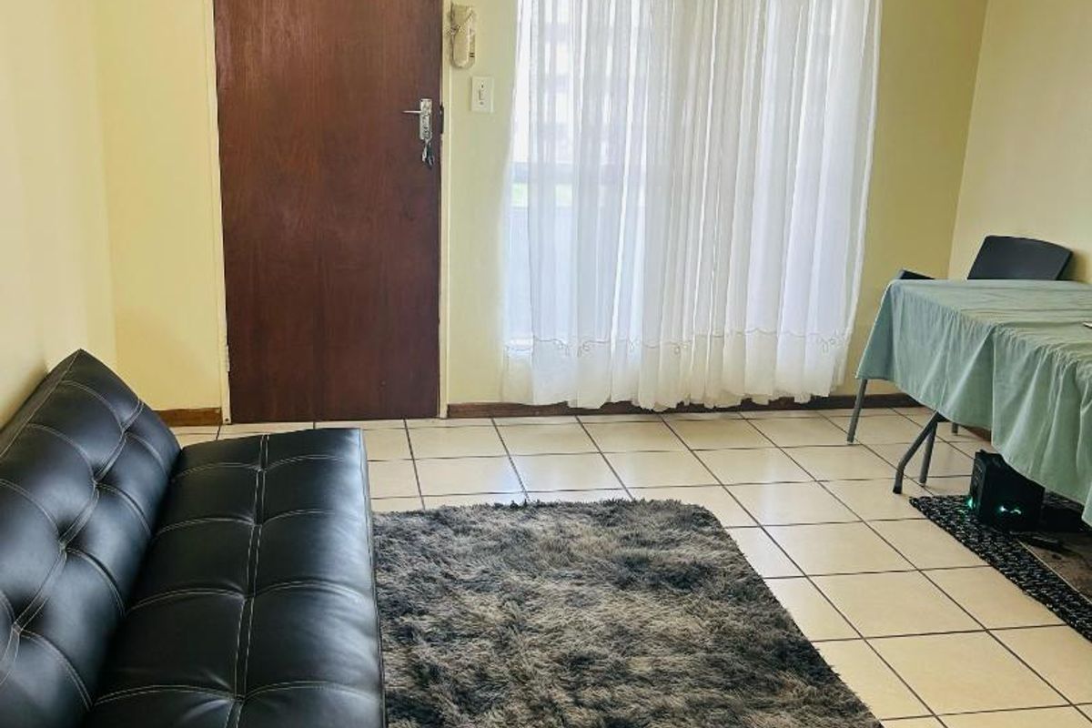 A living room featuring tiled flooring, an intercom system, and a sliding glass door leading to an outdoor area.