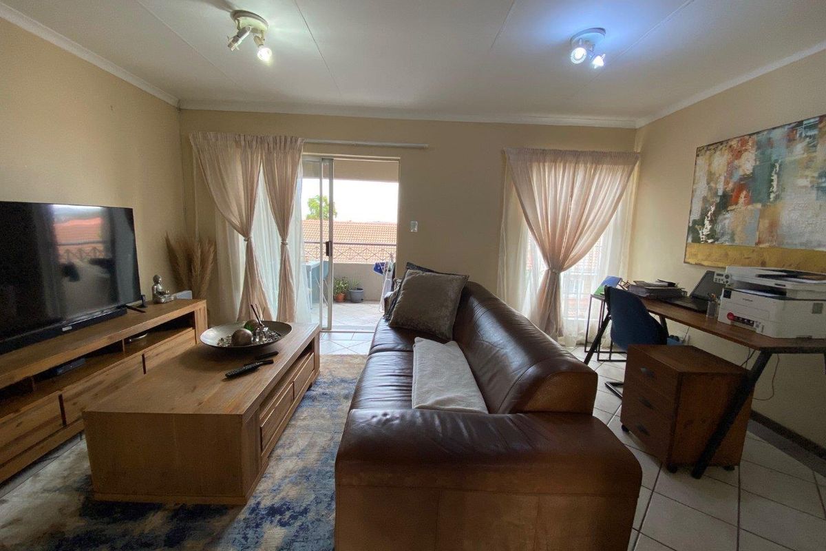 A living room featuring tiled flooring and sliding glass doors that open onto a balcony, providing natural light and access to outdoor space.