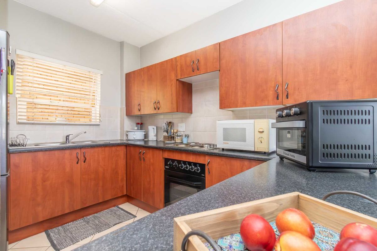 A functional kitchen featuring wood-look cabinetry, dark laminate countertops, a built-in oven, and a tiled backsplash.
