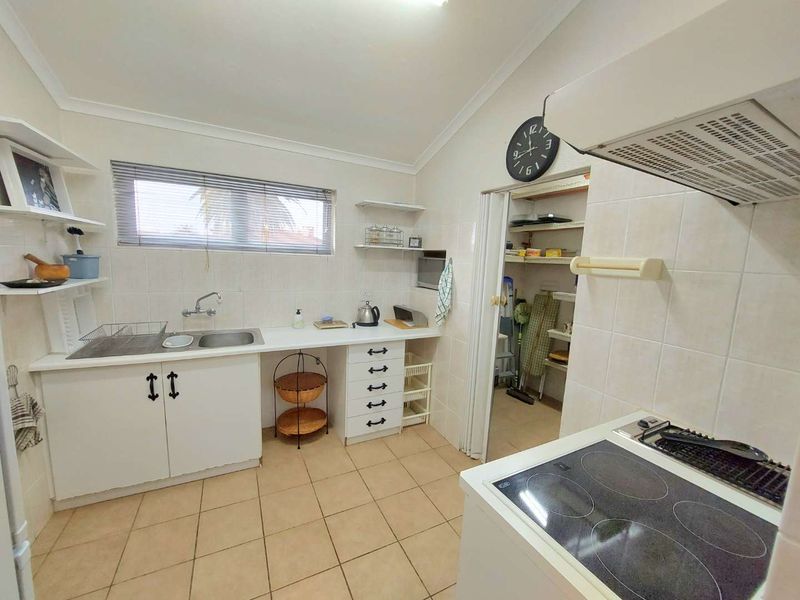 Functional kitchen featuring tiled flooring, built-in cabinetry, electric cooktop with extractor, and a convenient walk-in pantry.