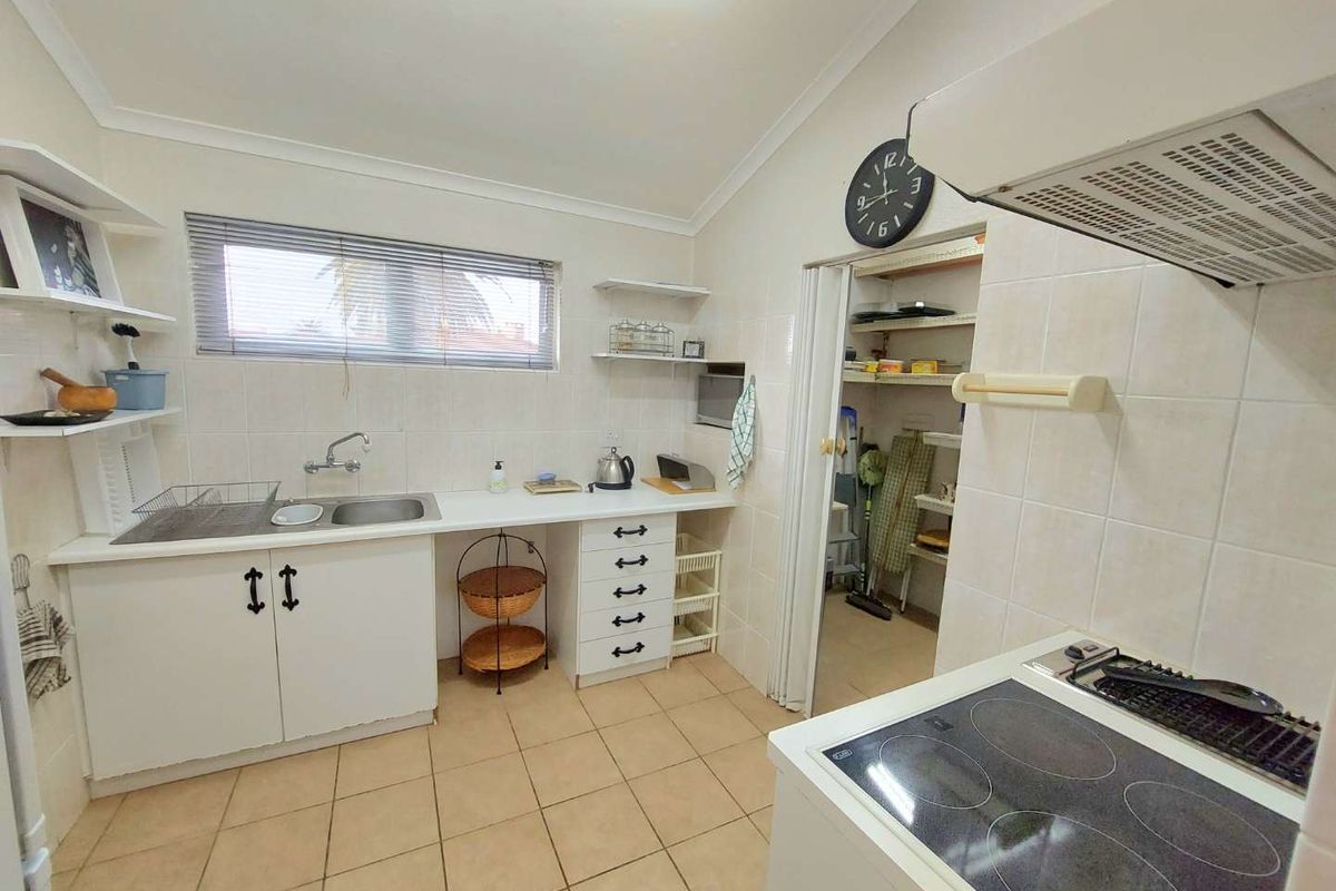 Functional kitchen featuring tiled flooring, built-in cabinetry, electric cooktop with extractor, and a convenient walk-in pantry.
