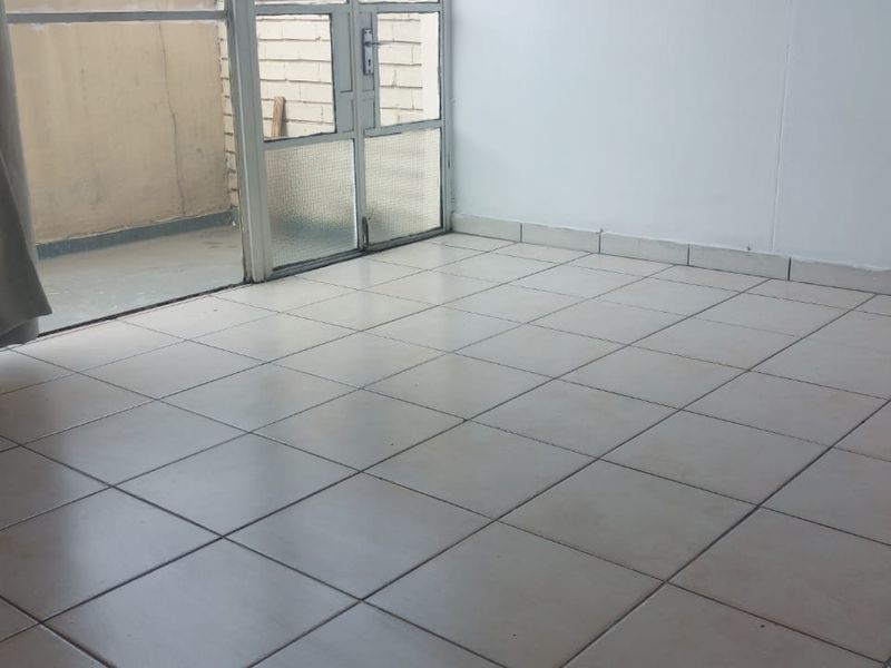 An empty living area featuring ceramic floor tiles and a sliding glass door leading to an outdoor space.