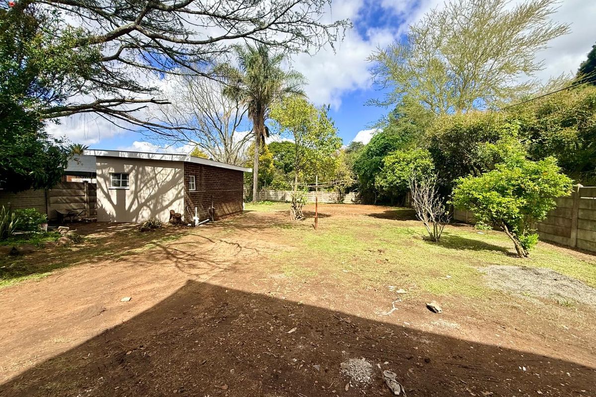Spacious rear garden featuring a brick outbuilding, precast boundary walls, and mature trees, offering significant potential for landscaping and outdoor development.